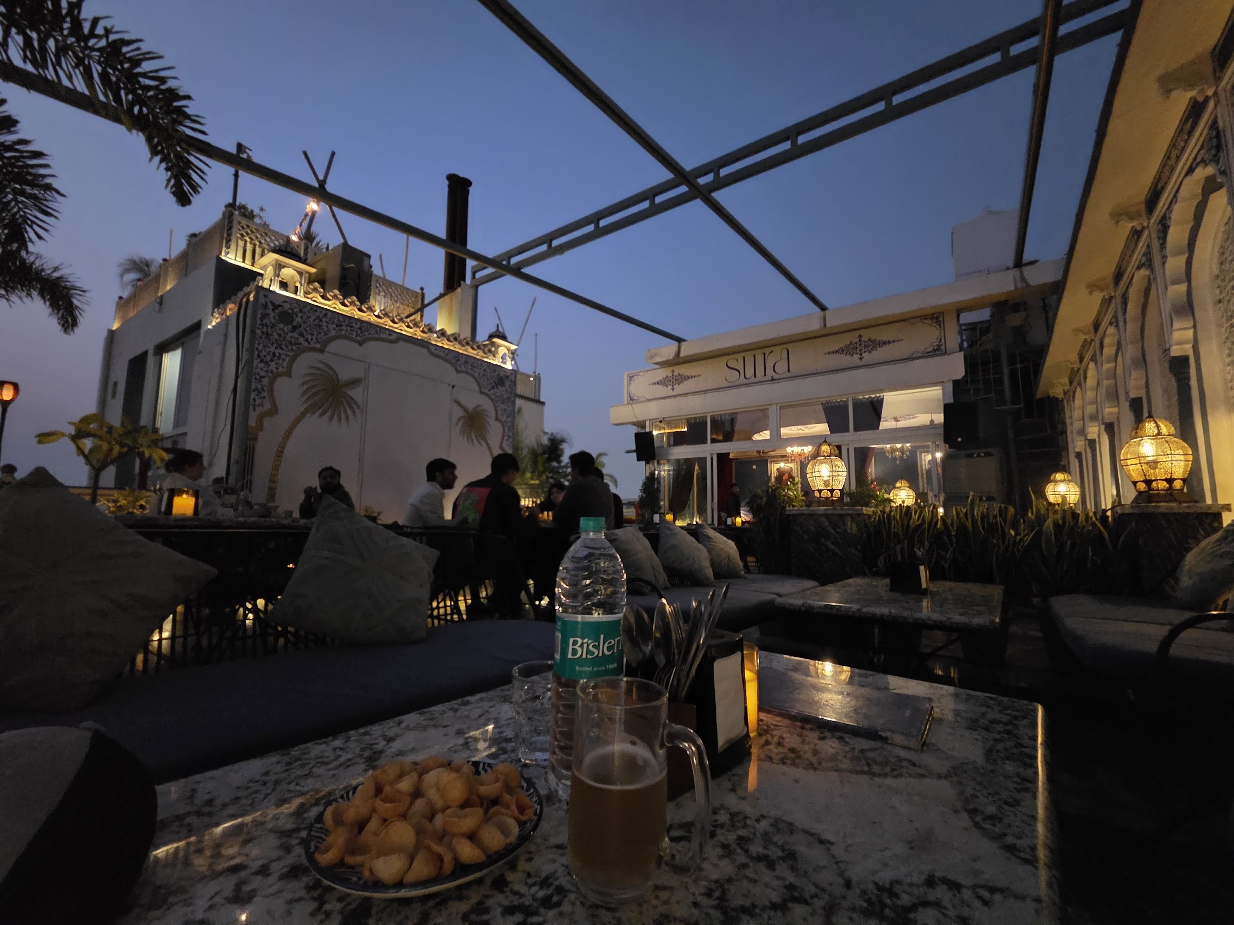 The Sura rooftop bar at dusk, signage glowing against the Jaipur skyline